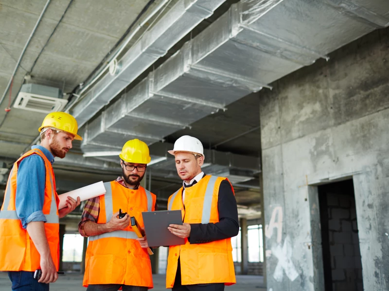 Drie mensen op de bouw die samen een bespreking hebben, om te tonen dat Lean Six Sigma voor iedere sector waardevol is