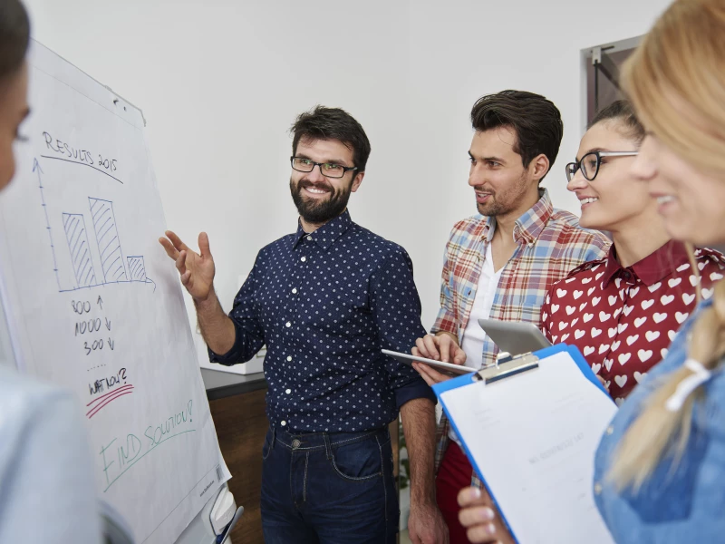 Een groep mensen die samen de resultaten bespreken, wat een onderdeel is van het werken met dagstarts en weekoverleggen binnen Lean