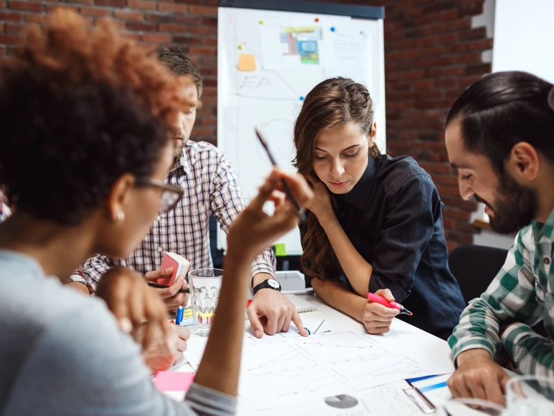 Vier collega's die een plan bespreken om FMEA risico's te verminderen.