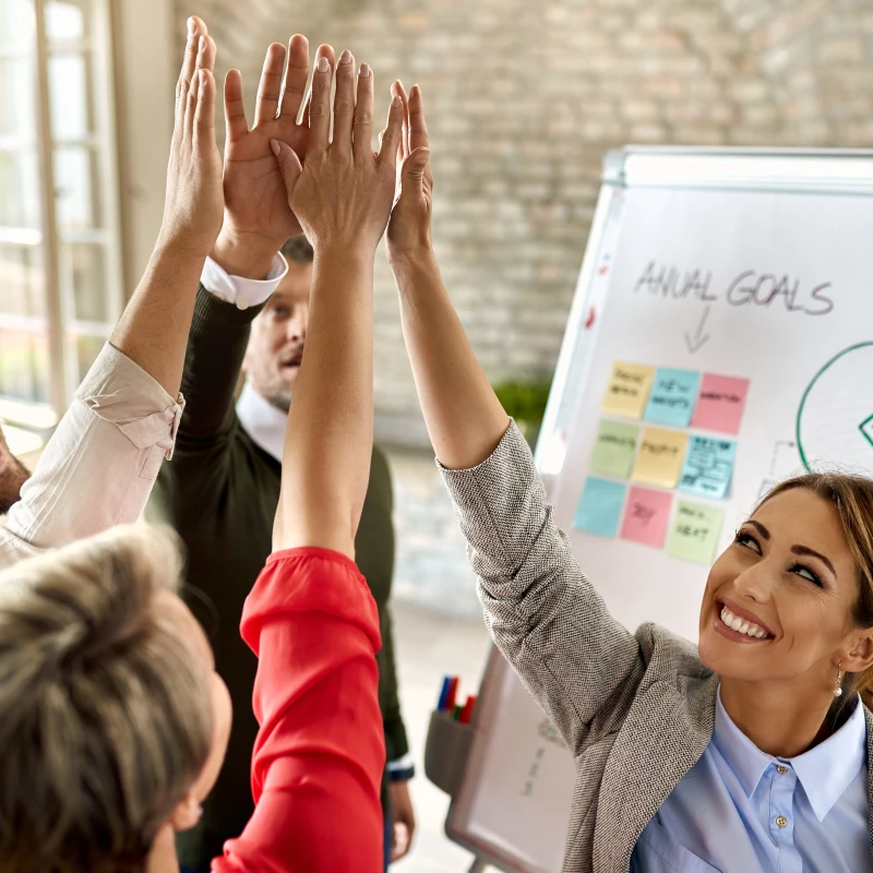 Groep mensen staan lachend naast een flipover en geven een high-five omdat ze blij zijn het de resultaten van hun projecten