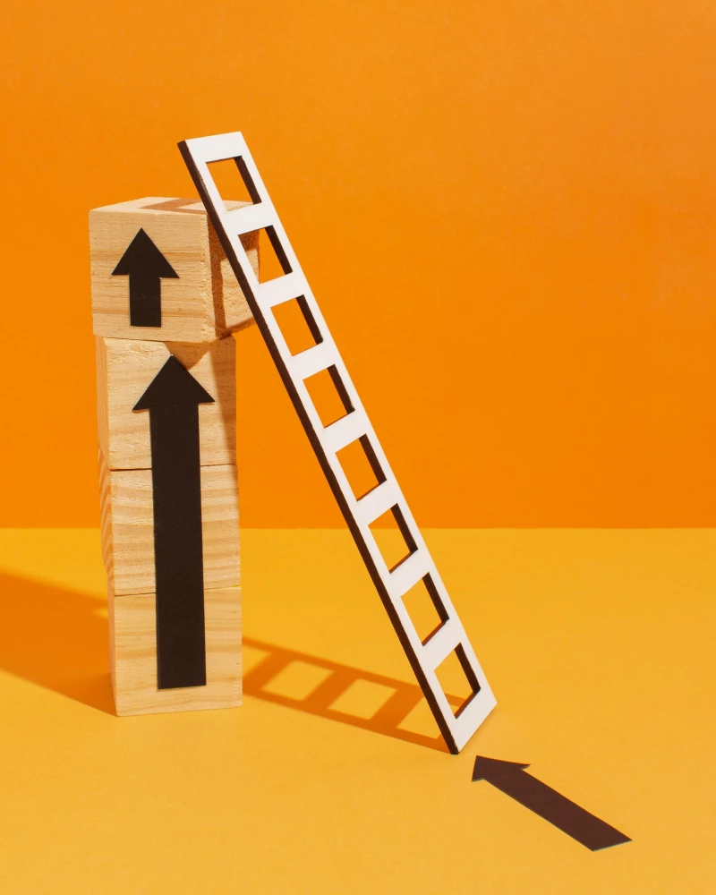 Stapel houten blokjes met een ladder daar tegen aan als symbool van processen optimaliseren