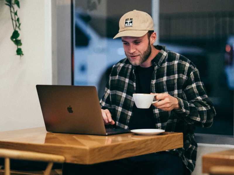 Deelnemer die met grote interesse naar zijn laptop kijkt met een kop koffie in zijn hand tijdens het volgen van een online Lean Six Sigma training