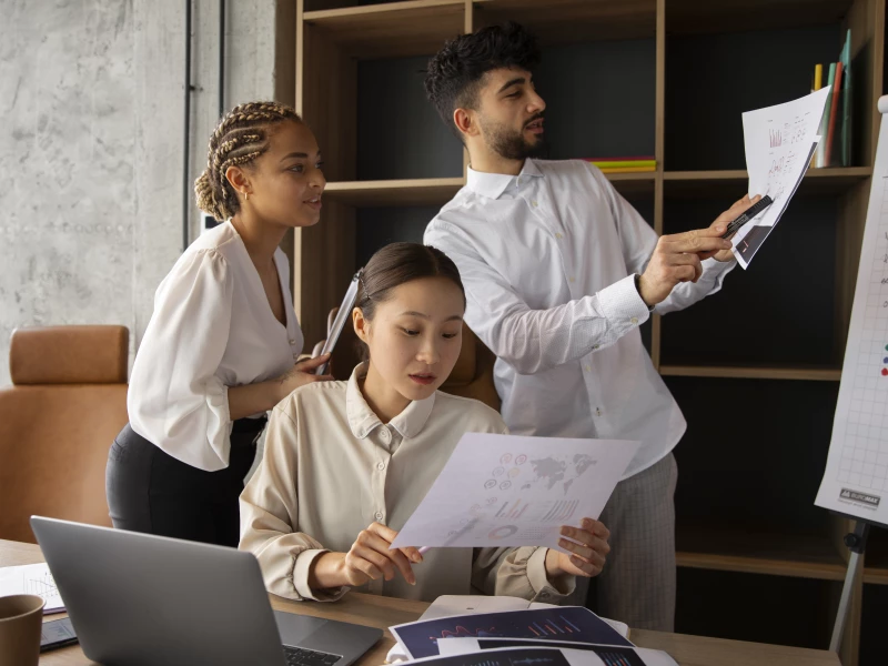 Kantoor medewerkers die informatie en grafieken raadplegen tijdens het analyseren van risico's tijdens FMEA.