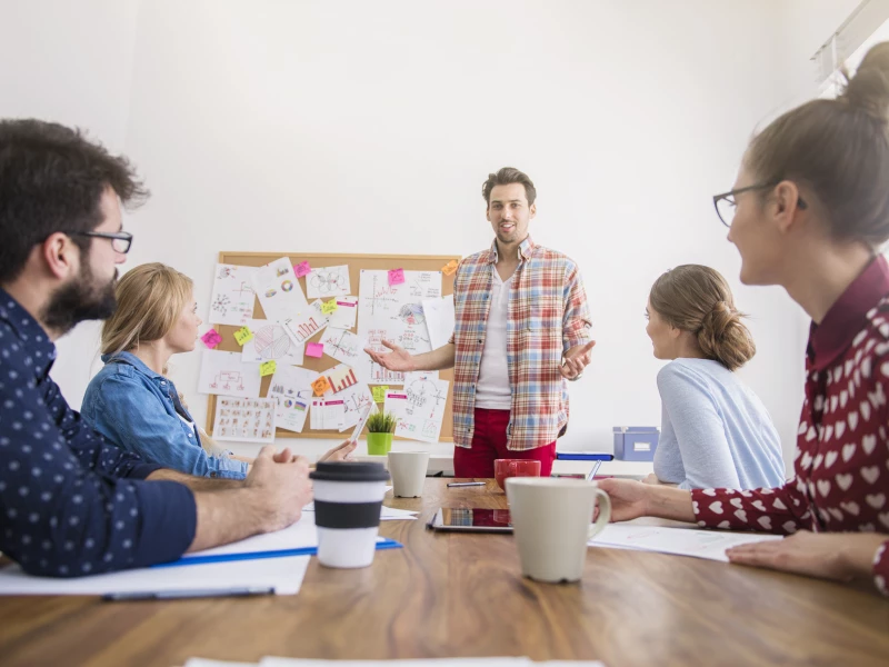 Een groep mensen rondom een tafel die samen problemen bespreken tijdens een Kaizen Event.