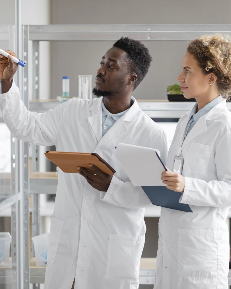 Twee onderzoekers die op een whiteboard verschillende Lean Six Sigma verbeterprojecten beschrijven