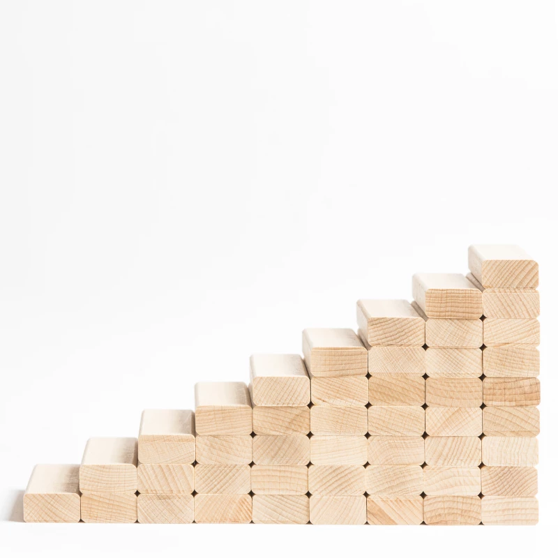 Een stapel houten blokjes waarbij iedere stapel hoger is dan de vorige, als symbool voor continue procesverbetering met de 5s-methode.