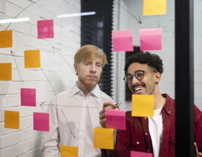 Colleagues looking at post-its through glass
